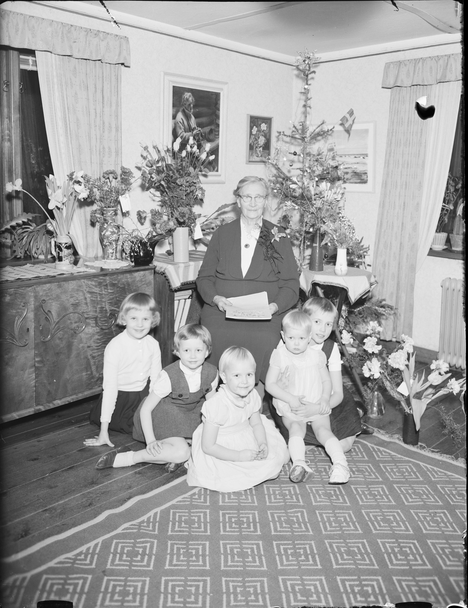 Kvinna omgiven av blommor och barn i hemmiljö, Östhammar, Uppland