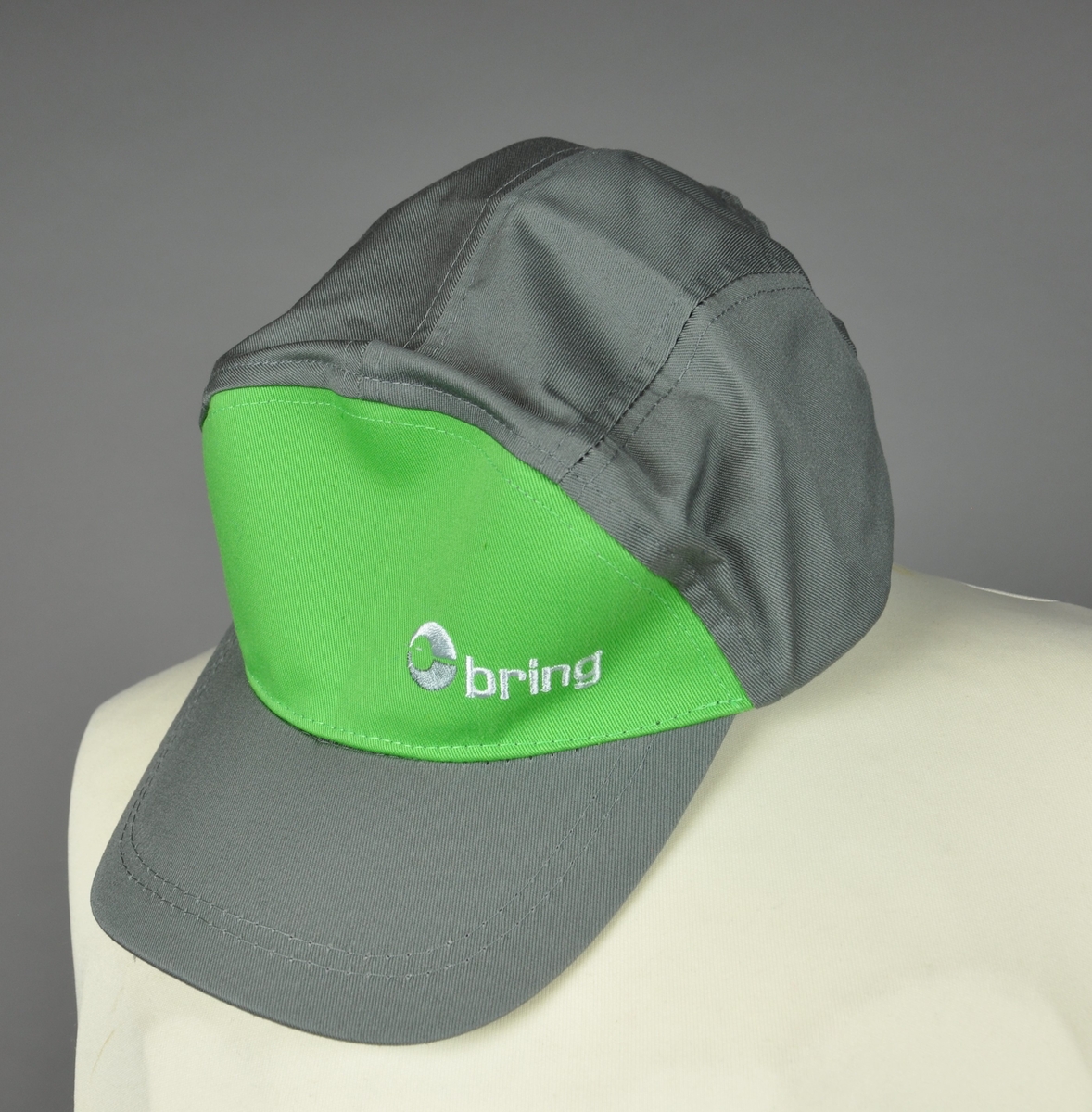 Caps med grønn og grå farge, og Brings logomerke brodert på fremsiden. Capsen har justering for størrelse bak.