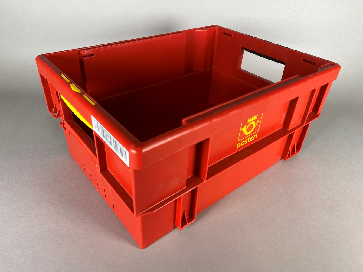 Rød kasse med postens logomerke på begge langsider. Utformet i legoklossprinsipp ved at den kan stables sammen med lignende kasser. Håndtakene har forskjellige farge, gul og svart. Postkassetten har også en påklistret strekkode.