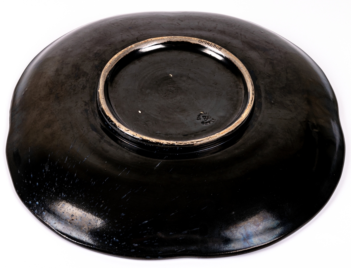 Stort svartglaserat fat, kallat "fyrklöverfat", av lergods, av Ewald Dahlskog, Bo Fajans. Modell D1.