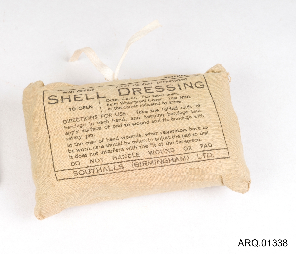 Bandasje i original emballasje; som er en sydd, lysebrun bommullspose, med instruksjon og produksjons-måned og år trykket på.