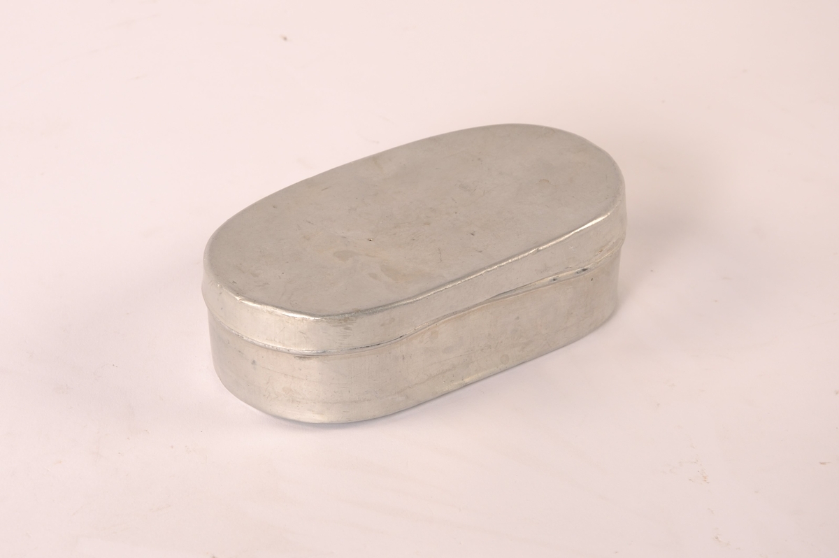 Oval matboks i metall med  avrundede hjørner og flatt, avtakbart lokk.