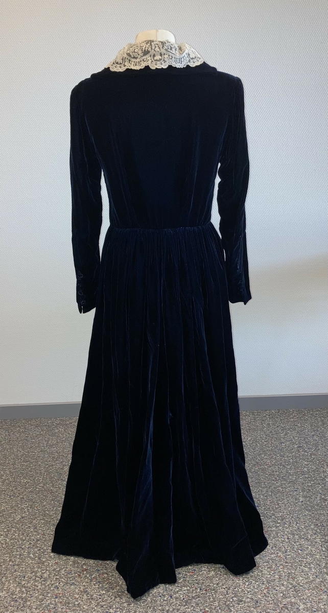 Den mørkeblå kjolen er datert til 1930-årene. Den ble sydd for Hedvig Sverdrup-Thygeson.
Det fortelles at kjolen er laget av den første viskosefløyelen produsert av cellulose fra trevirke som kom fra trevarebedriften Stangeskovene. Hedvig Sverdrup-Thygesons mann var aksjonær i Stangeskovene, og alle aksjonærkonene fikk noen meter av dette stoffet. Det er en sterk familiær tilknytning til Stangeskovene da selskapets grunnlegger, Nils Anker Stang, var Hedvigs morfar.
Ifølge etterkommere av kjolens første eier er kragen laget av italienske kniplinger.
