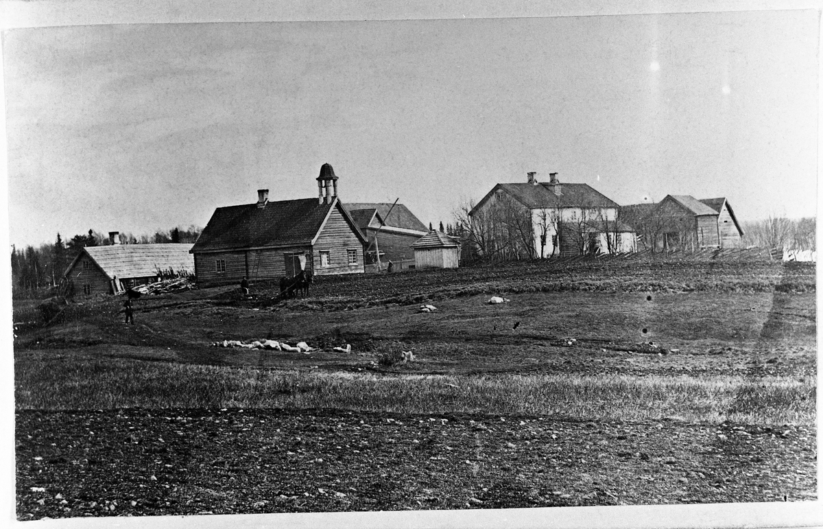 Pløying på Blilie, Eina, trolig før 1880. Gardstunet er her sett fra nordvest. Fraa venstre er størhus, drengestue, forlåve, do, hovedbygning, stabbur, fjøs og stallåve. Ved sida av drengestua ses vippe og brynn. Bak forlåven var det et bryggerhus.