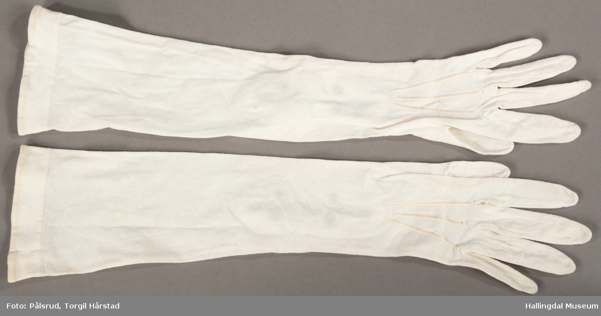 Et par hvite bomullshansker med to lyse, runde perlemorstrykknapper på hver hanske.