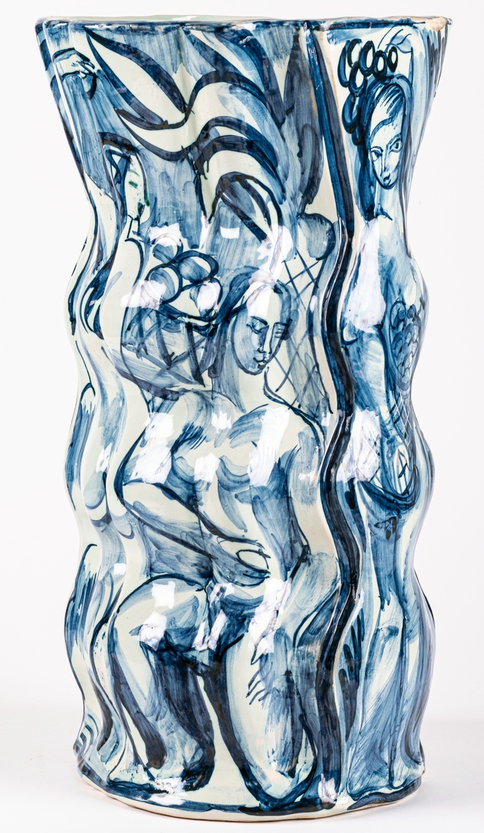 Vas, Bo Fajans, design Allan Ebeling. Vasens form är vågformad med en trattliknande avslutning, blå figurdekor på grå tennglasyr, växter och kvinnofigur.