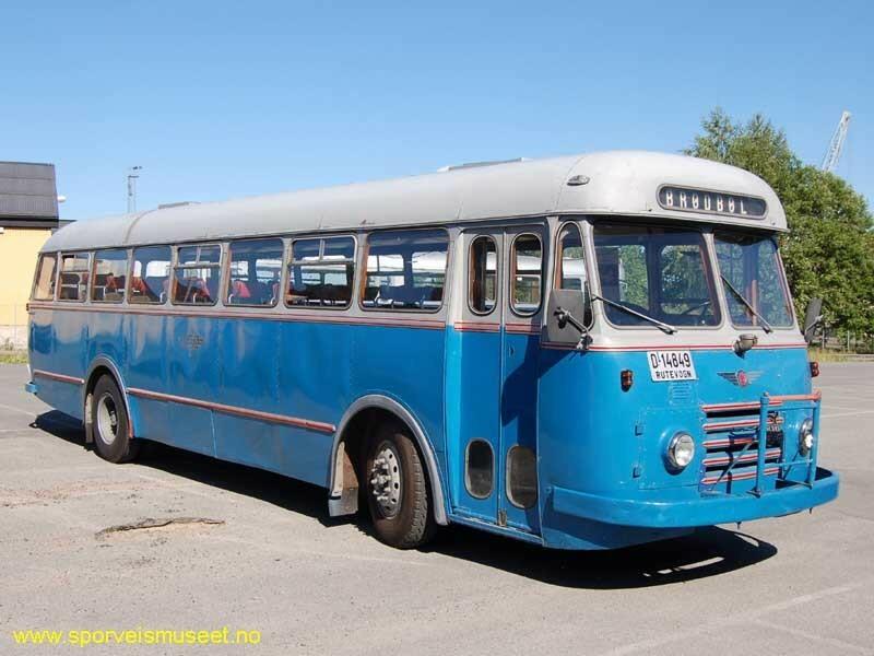 Buss i en lys blå til turkis farge og et grått tak. Bussen har røde detaljer med striper i front og på sider. 