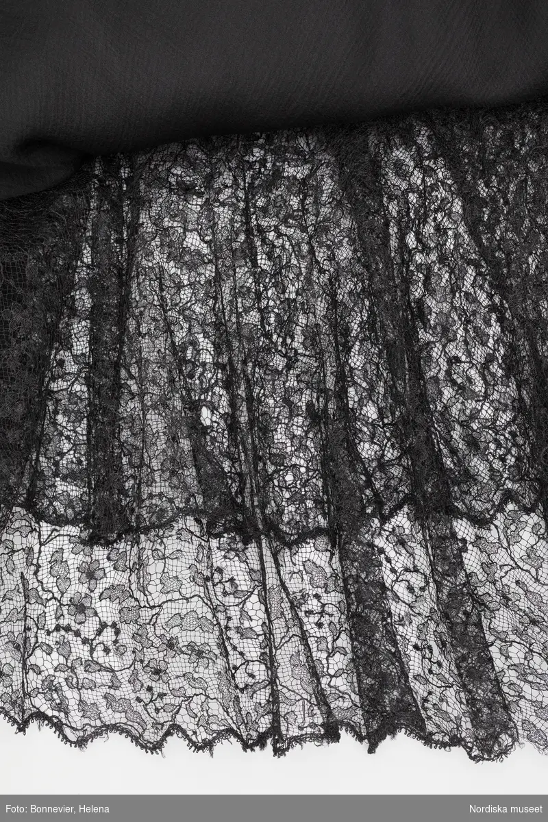 Klänning monterad på docka. Festklänning med detaljer av tyll. Originalplagg från Coco Chanel, troligen från tidigt 1930-tal. Den har tillhört Margit Graffman (1900-1991), chef för NK:s konfektionsavdelning 1931 till 1953.