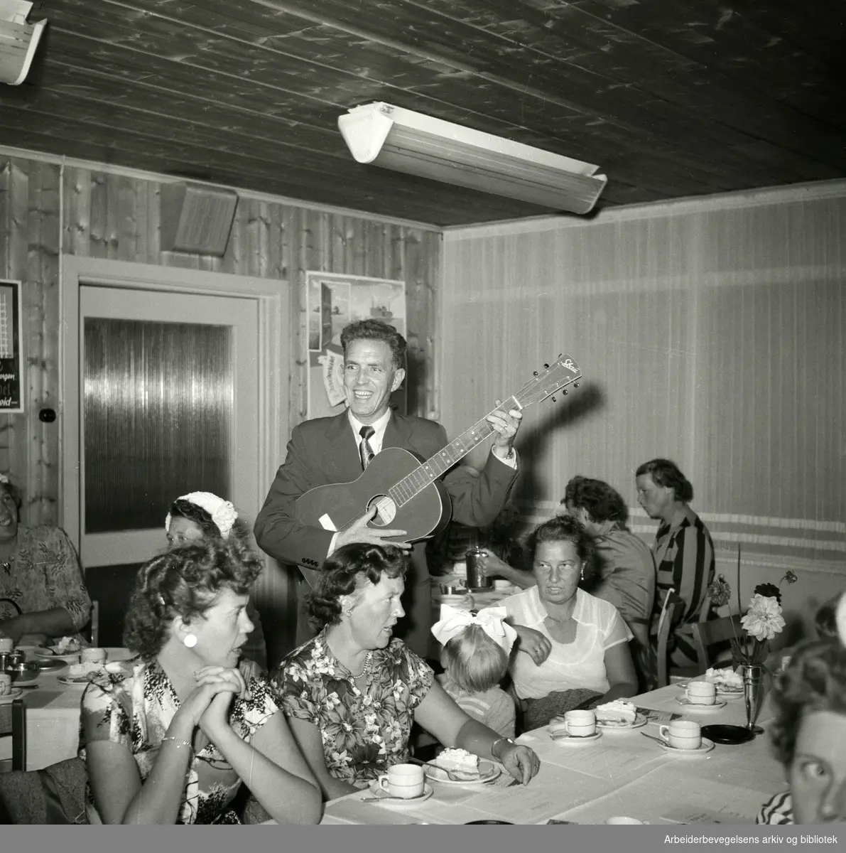 Arbeiderbladets husmortimer på Helsfyr hotel i Oslo. Tryggve Aakervik (1917-2006) "Mannen med den røde gitar" synger og spiller. September 1955.