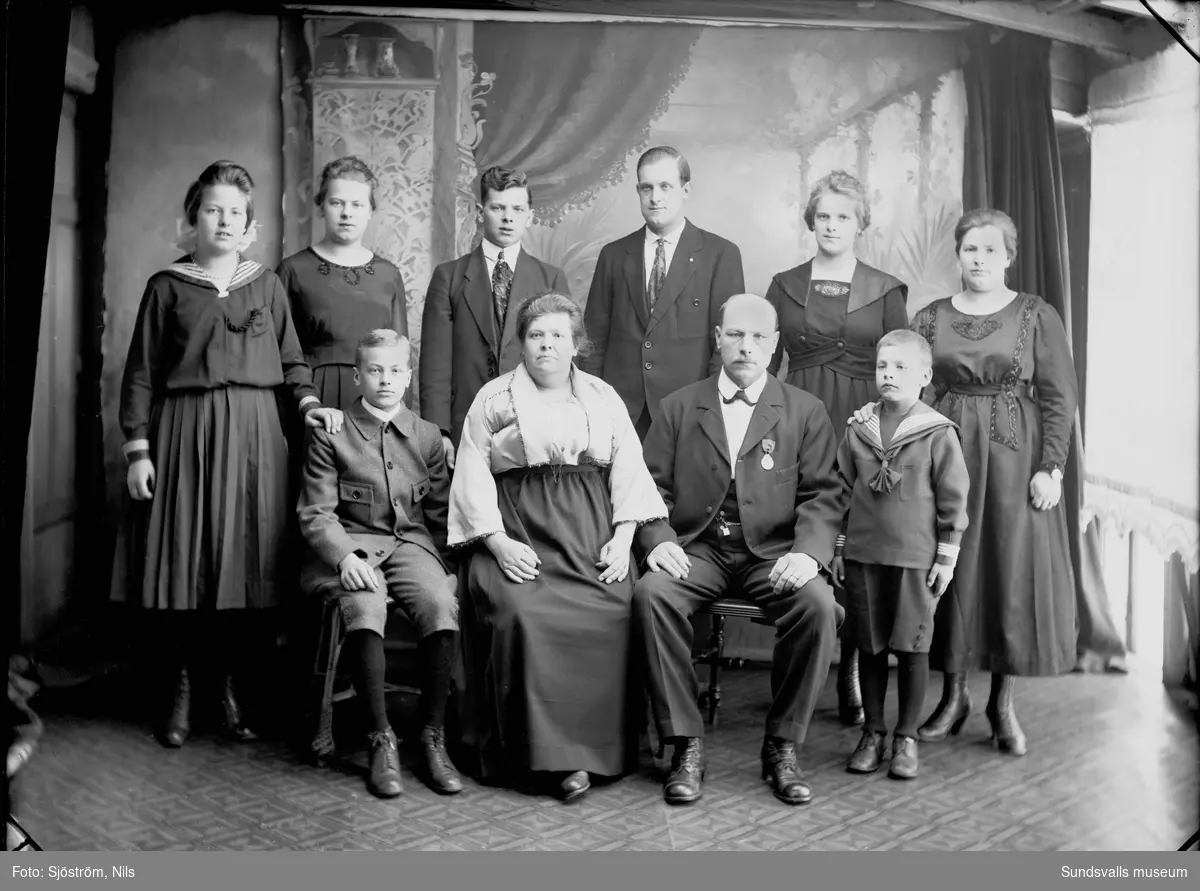Ateljéporträtt/familjefoto med en kvinna och en man i centrum och (troligen) deras åtta barn.