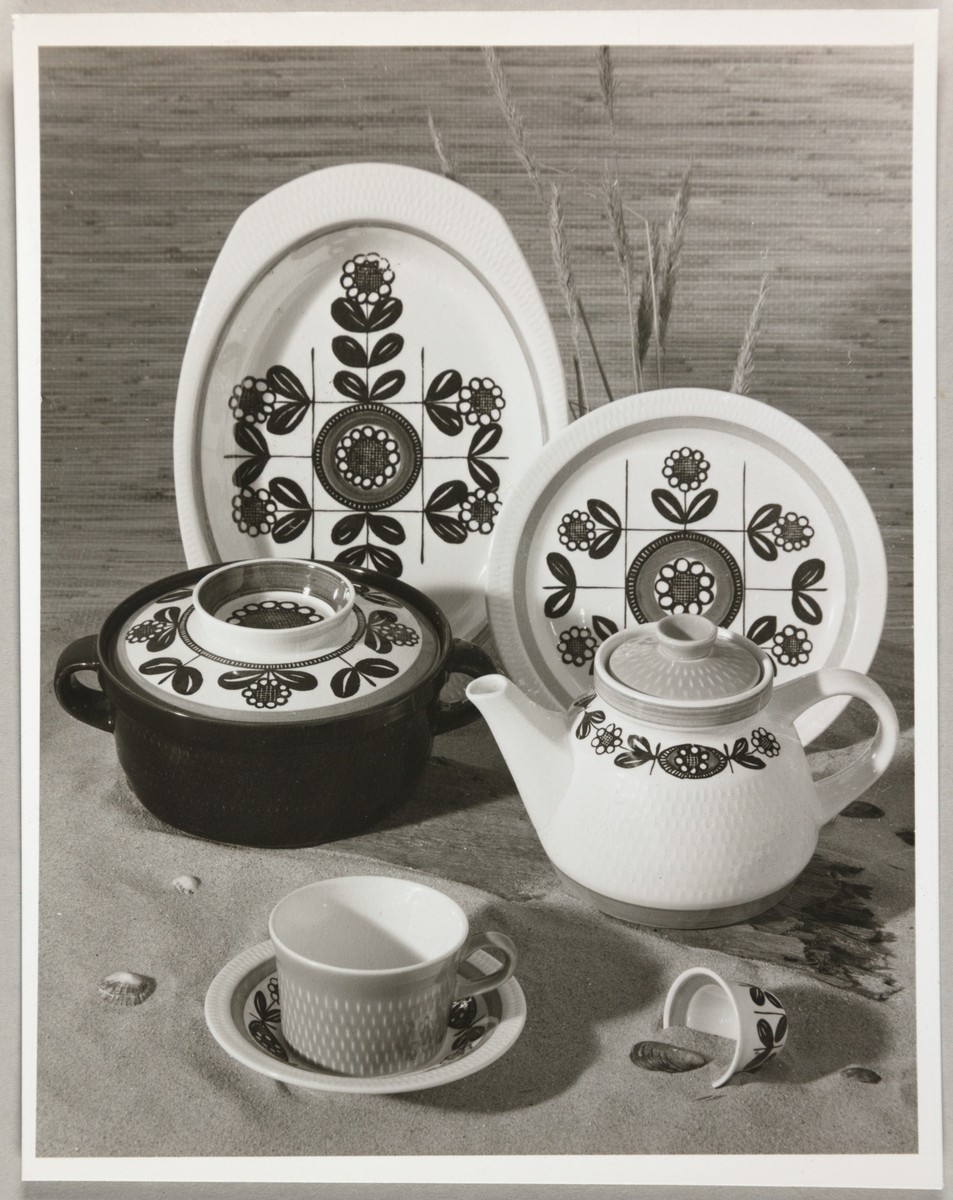 Reklamefoto av serviset "Kon-Tiki" fra Stavangerflint A/S. Avbildet sortiment viser en kopp med skål, tekanne, gryte, tallerken og fat.