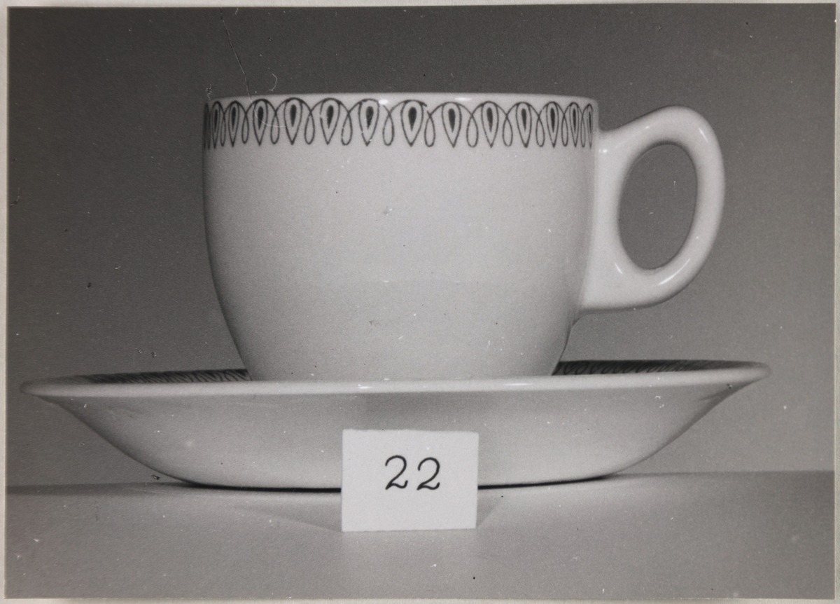 En kaffekopp med underskål fra Stavangerflint A/S. I forgrunnen står en lapp med nummeret 22.