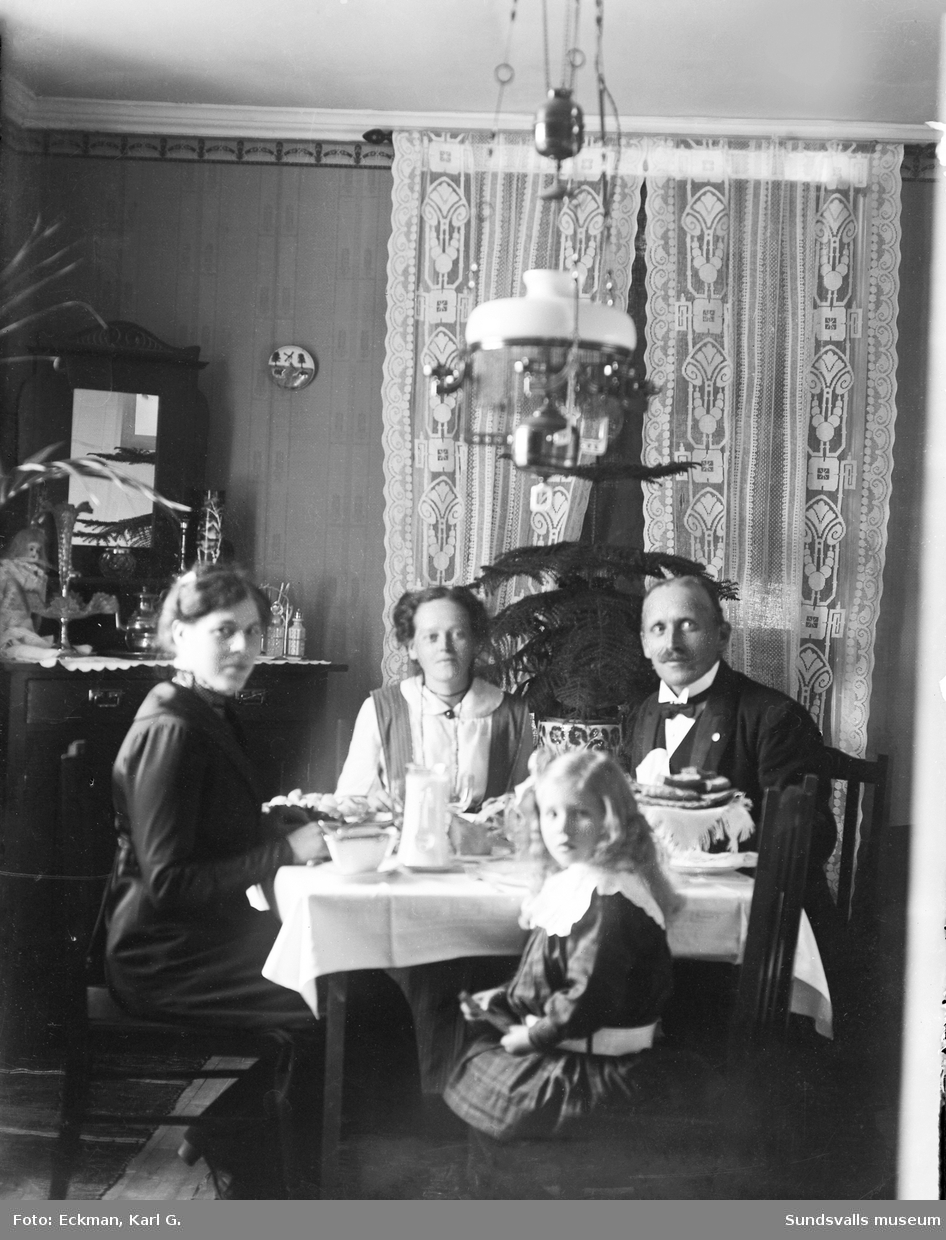Fotografens hustru Hildur Eckman sitter vid ett dukat kaffebord tillsammans med en annan kvinna och en man samt en flicka, i Indal. Ur Karl Eckmans samling.