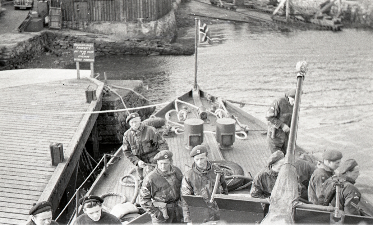 KNM HITRA fortøy til kaien i Scalloway Shetland rett før avgang til Bergen 14/5 1945. Deler av mannskapet, samt sersjanter og korporaler fra Lingekompaniet ses på fordekket. Prins Olavs slipp ses foran fartøyet. 