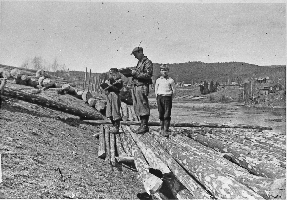 Tømmermåling på Ebbesberglandet, ca. 1945. Liten og stor fløyholder: Asbjørn Mollerud og Erik Mollerud. Helge Ebbesberg til høyre.
