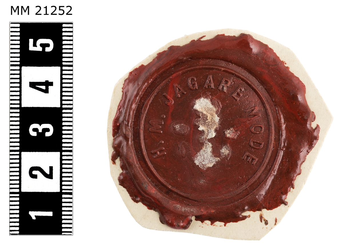Sigillavtryck av rött lack på papper. I mitten krönt stockankare omgivet av tre kronor. Längs kanten text: "H.M jagare Mode".