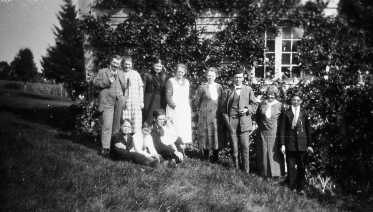 Gruppeportrett av en familie i hagen foran et hus.