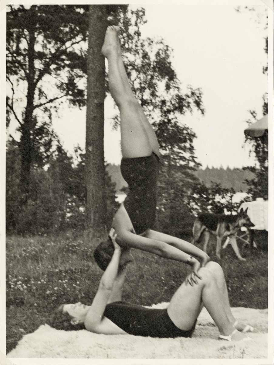 Två gymnastikflickor övar akrobatik på en gräsmatta. 1930-tal.
