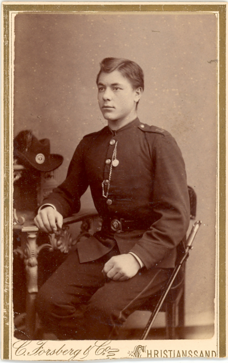 Olav Pålskås i militær uniform, sitjande i fotoatelier.
