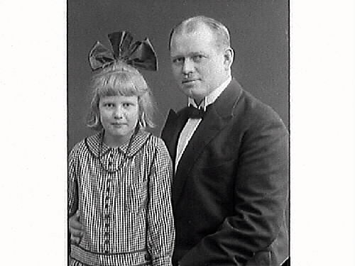 Ateljébild av järnhandlare Arvid Ekström och dottern Harriet. Flickan har en smårutig klänning och enorm rosett i håret.