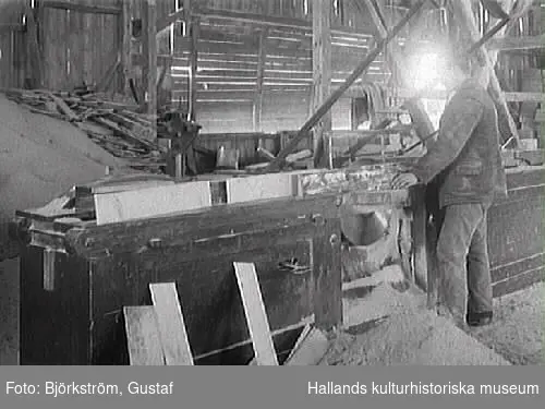 Interiör av snickerifabrik på Varbergs Träförädling. En man står vid en såg och kapar korta bräder.
(Se även bild nr GB2_1155)