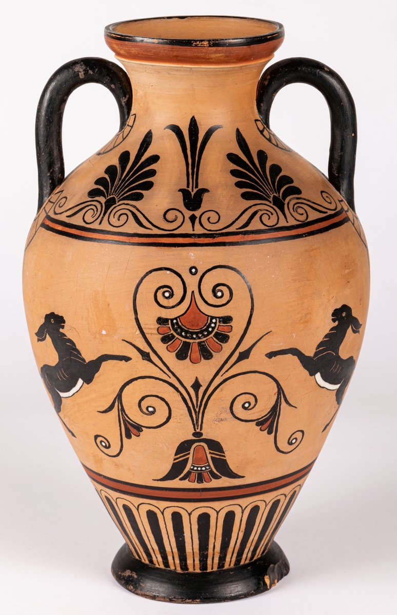 Amforaliknande vas med två hänklar, lergods, med handmålat mönster i antikiserande stil i svart, rött och vitt i form av bladdekor och fyra fantasidjur. Dekoren målad på det brända godset, ingen annan glasyr.