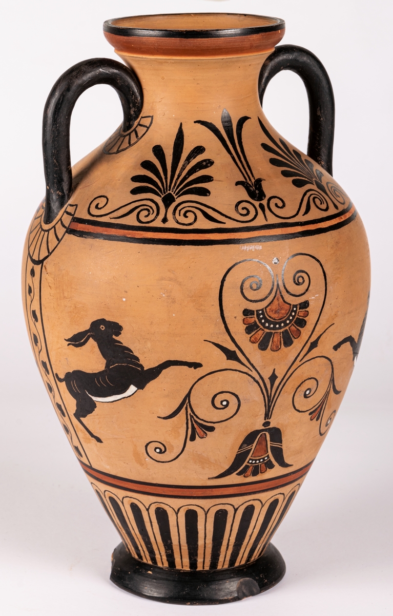 Amforaliknande vas med två hänklar, lergods, med handmålat mönster i antikiserande stil i svart, rött och vitt i form av bladdekor och fyra fantasidjur. Dekoren målad på det brända godset, ingen annan glasyr.