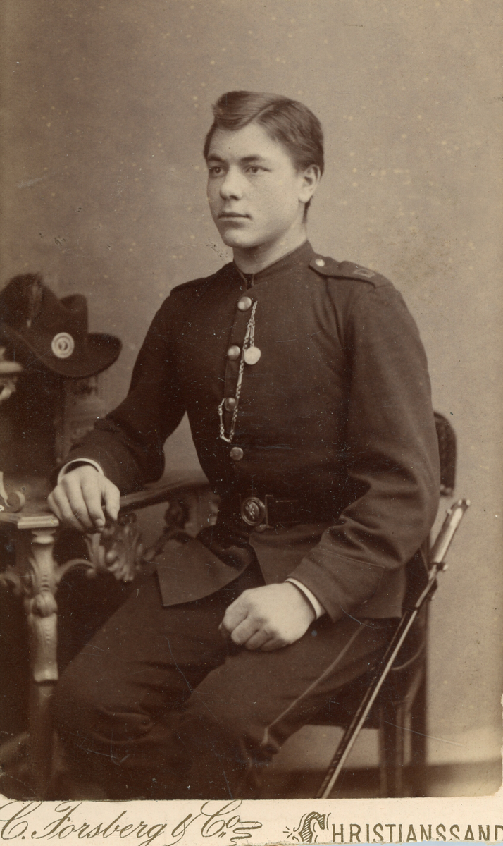 Olav Pålskås i militær uniform, sitjande i fotoatelier.