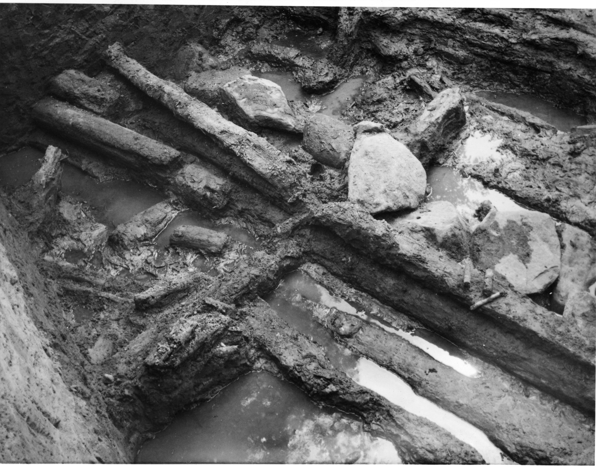 Närbild på timmer och stenar vid Rumlaborg i Huskvarna. Lämningarna påträffades i norra delen av schakt G på sydvästra sidan av borgkullen i samband med en arkeologisk undersökning sommaren 1942.