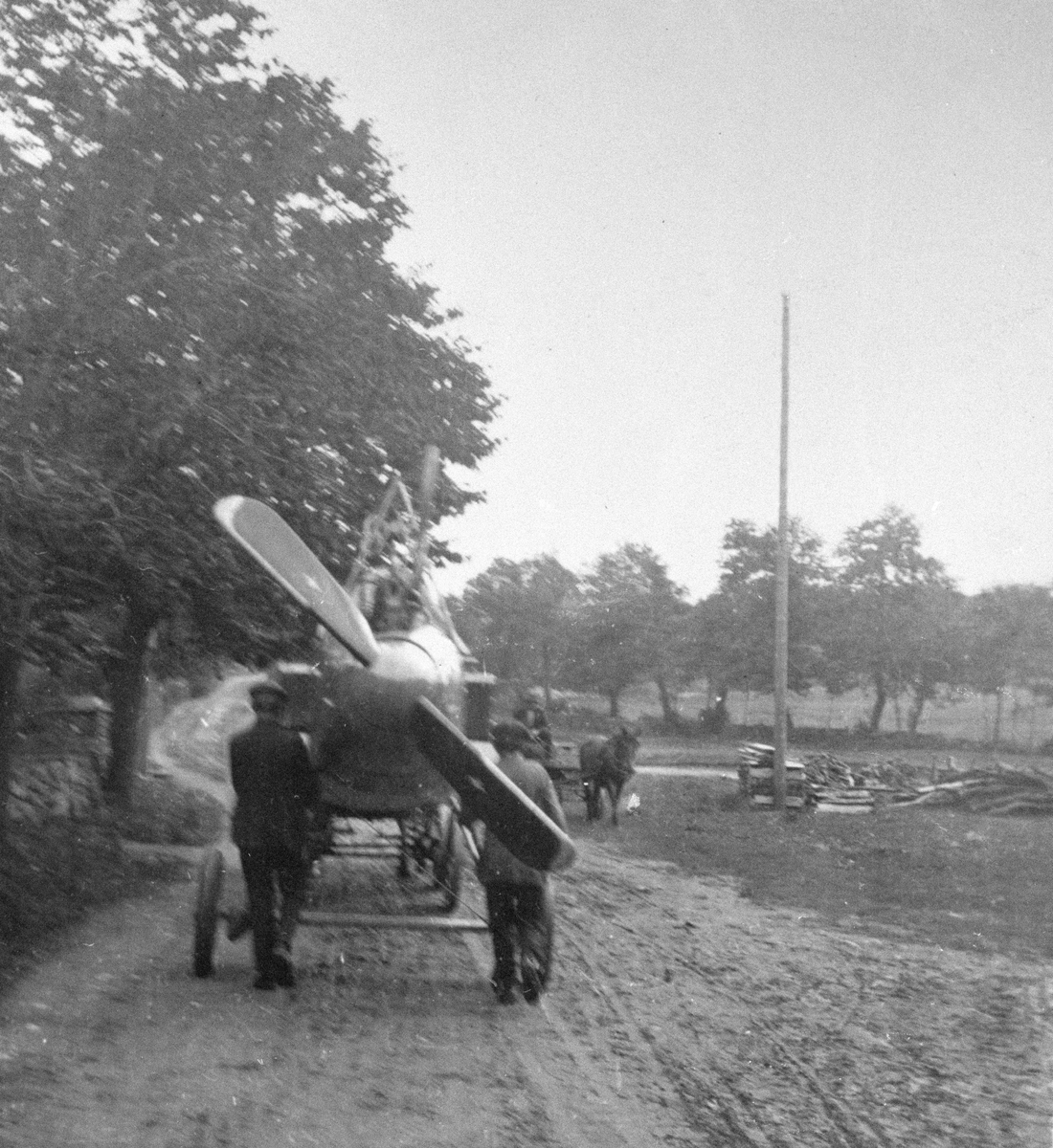 Flygplan Thulin FA med vingar bortmonterade bogseras längs en landsväg i Ljungbyhed, omkring 1918. Vy bakifrån.