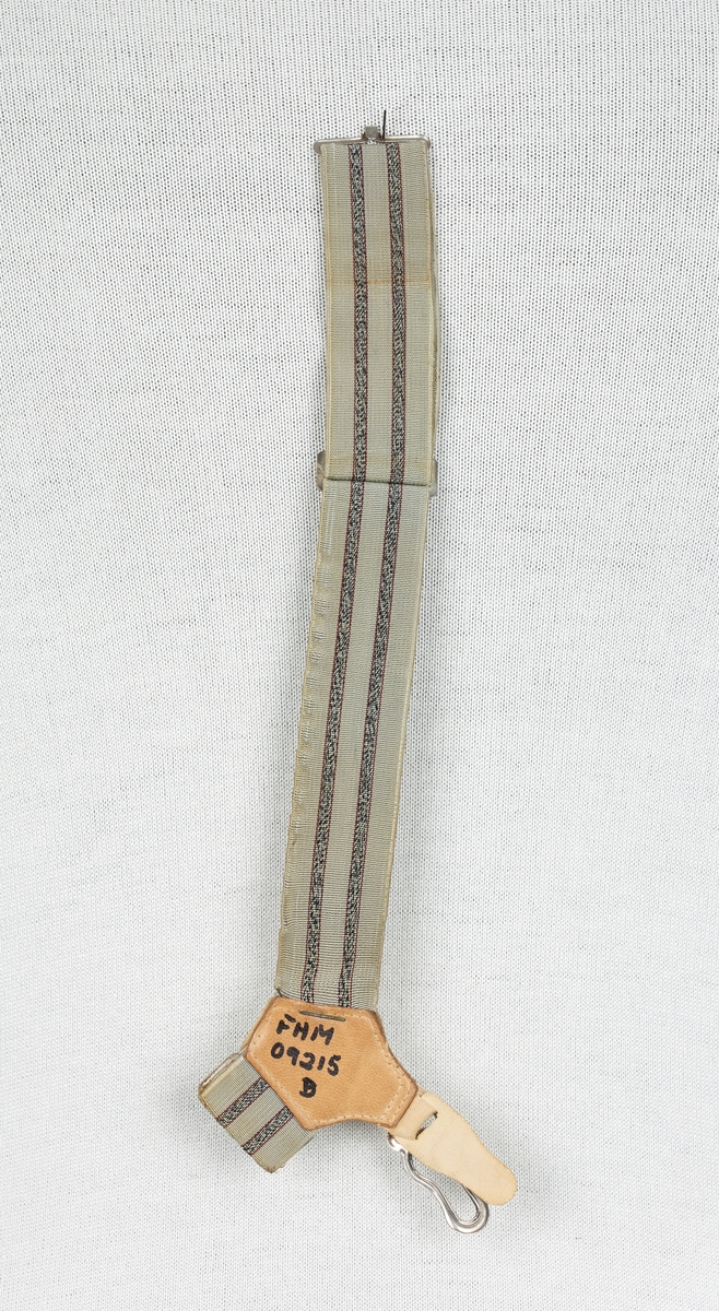 Regulerbar strikk med lukkemekanisme rundt legg og en festeknapp mot sokken. En ensfarget rød og to stripet i grå og blå og beige og grå