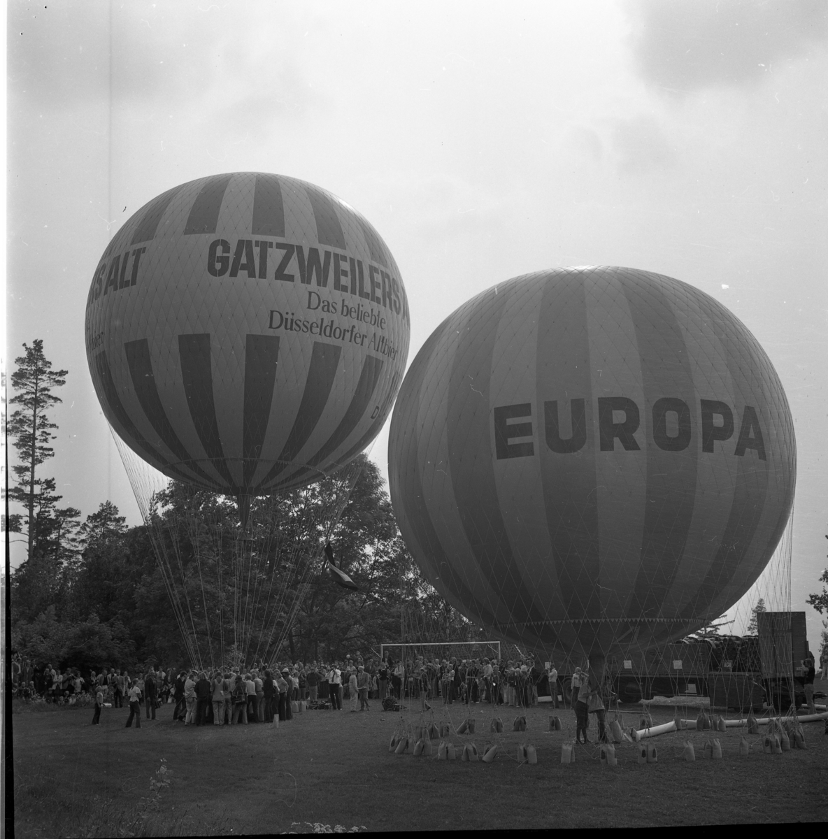 Två ballonger på väg att lyfta, märkta "Gatsweilers Alt" respektive "Europa"