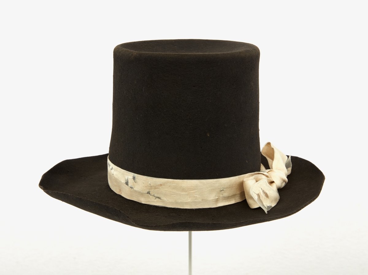 Hatt tillhörande Gustav III:s daluniform. Hög hatt av svart filt. Ombunden med vitt sidenband, knutet i dubbelögla med långa ändar.