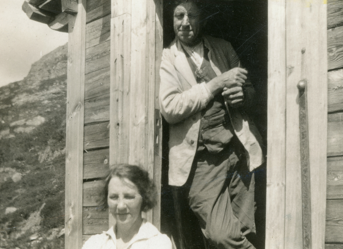 Torleiv Stadskleiv og ei ukjent kvinne i døropninga i hytta til Stadskleiv, Skrubbehiet, på Lifjell.