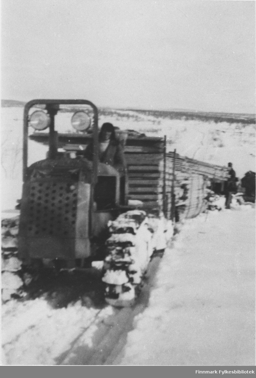 Materialtransport Alta-Kautokeino. Bilde av en beltebil som trekker flere sleder med materialer. En mann kjører beltebilen.