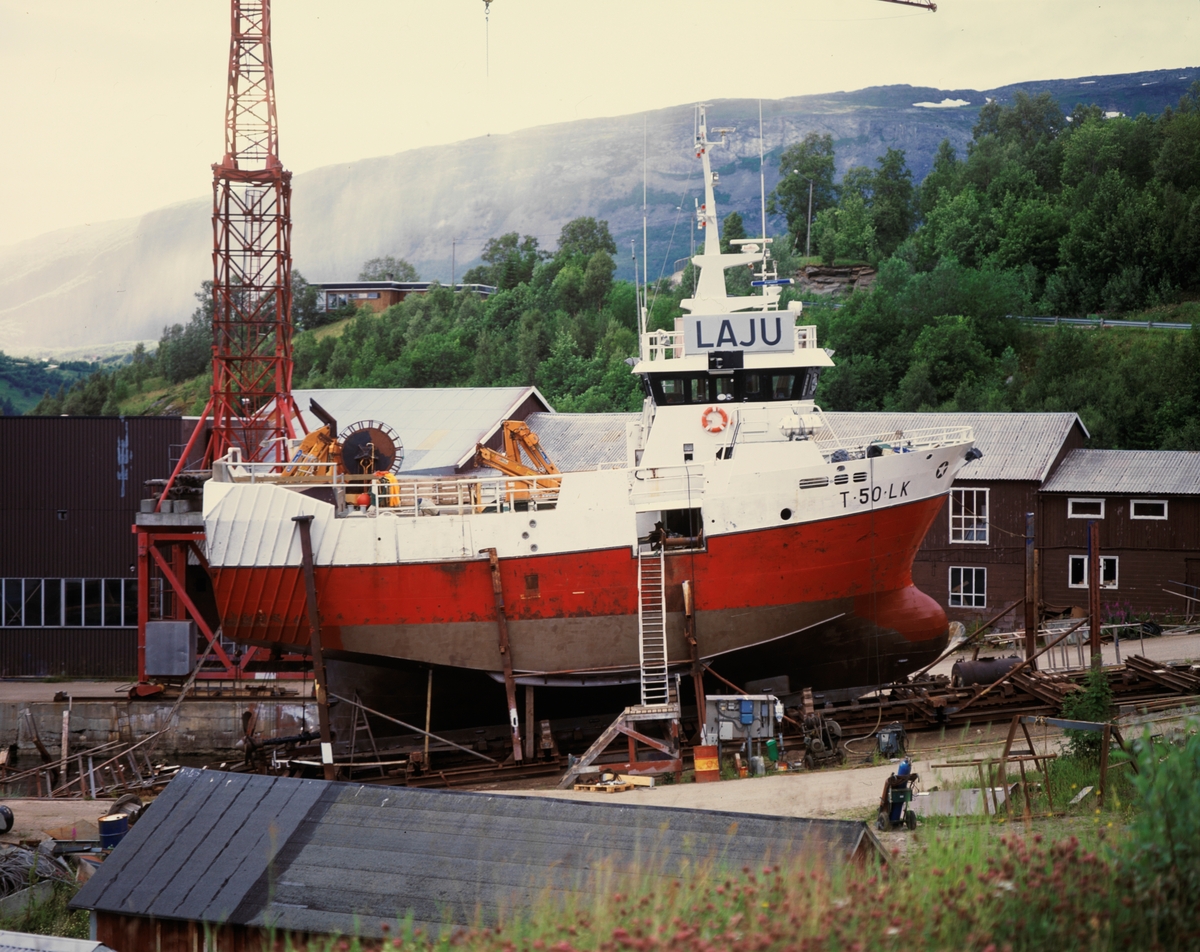 Foto av skipet Husøysund på land. Fiskebåten har registrering nr. T 0050 LK og kjenn. signal LAJU.  Group no. 64-35-07-00   Picture no. 433066  Båtslipp Grovfjorden mekaniske verksted sommer