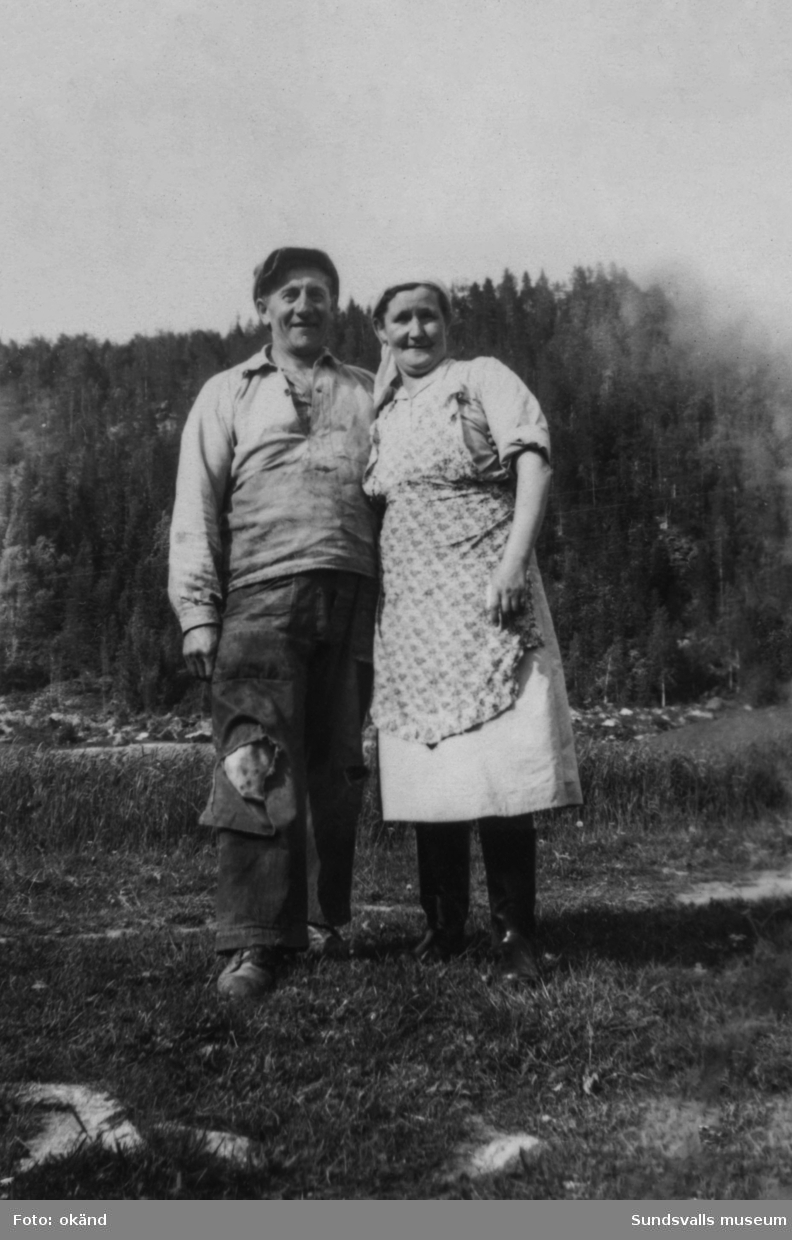 Porträtt av ett äldre par utomhus. På bildens baksida står: Manne och Lydia Öhlund, Lövsätt. Ur en samling från Byn, Norrbäcken, Sättna.