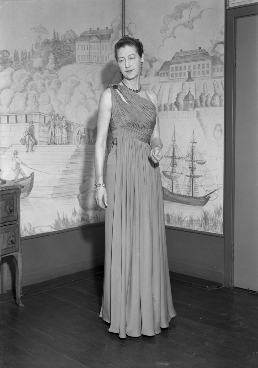 Thor Bendz Kielland (1894-1963) sin andre kone, amanuensis Edle Due Astrup (1903-1978). Hun poserer sittende i fotsid gallakjole og tiara.  Kielland var direktør for Kunstindustrimuseet fra 1928 til ca. 1960.