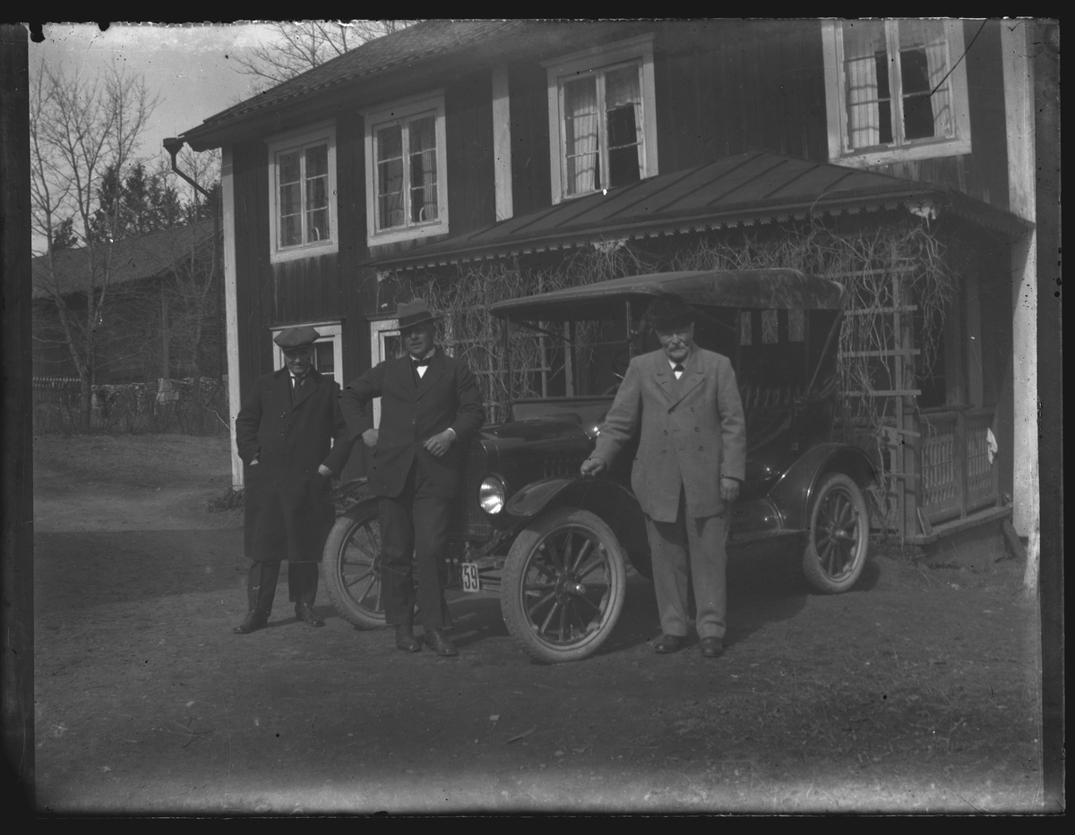 Grupporträtt, tre personer med bil framför gårdens veranda.