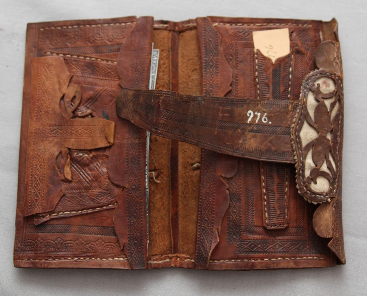 Plånbok i läder med pressad dekor. Med två sedelfack och ett mindre fack.