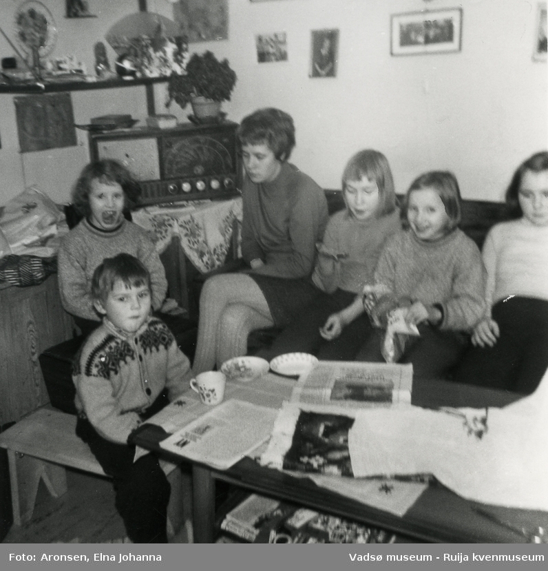 Barn og voksne har benket seg i sofaen foran radioen og hører på lørdagsbarnetimen, ca 1969. Fra venstre foran, Steffen Aronsen, Heidi Søfting, Ragnfrid Aronsen, Liv-Erna Aronsen, Aud Lillian Søfting og Joronn Aronsen.