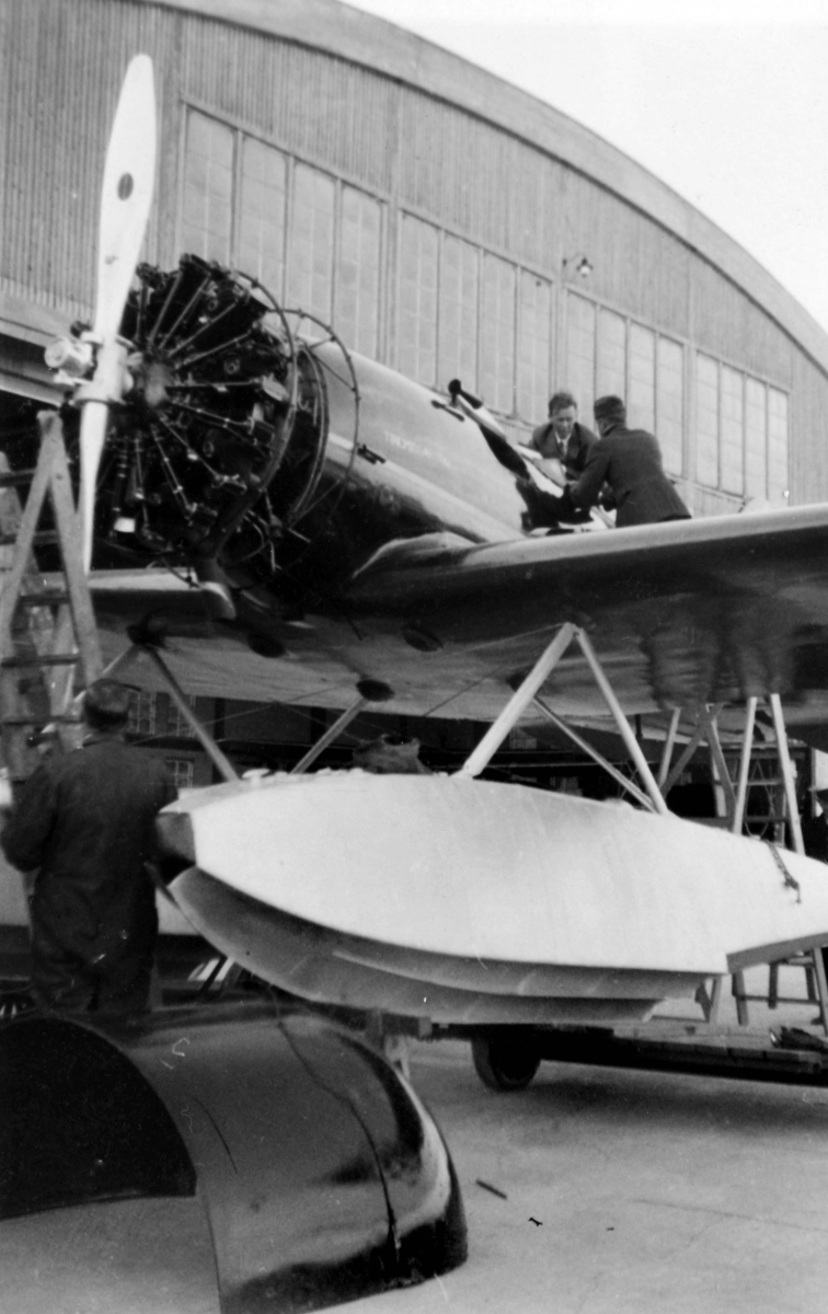 Service av flygplan Lockheed 8 Sirius ''Tingmissartoq' framför hangar på F 2 Hägernäs vid Charles Lindberghs besök i september 1933. Mekaniker i arbete. I förarsitsen sitter Charles Lindbergh.
