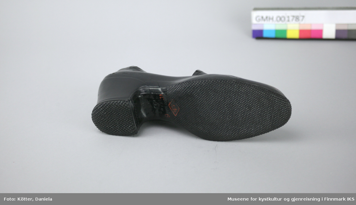 Denne kalosjen er en overtrekkssko av svart gummi. Den er foret med stoff og formen er egnet til damesko med høyere hæl.

