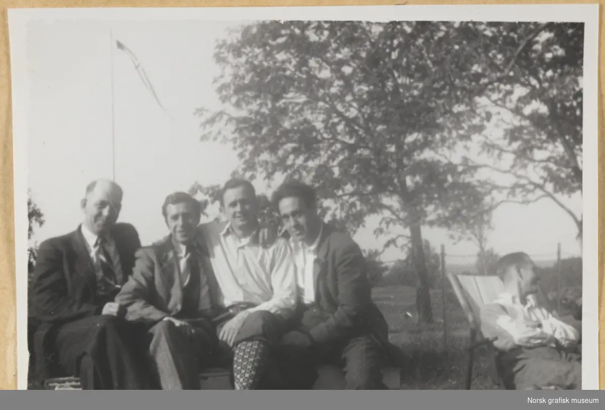 Utendørs. Fem menn sittende i en hage. Trær og flagg på stang i bakgrunnen. Fotografert i forbindelse med Vestlandsk Trykkerstevne i Bergen, 1946.