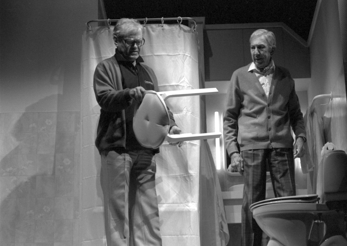 Scene fra Nationaltheaterets oppsetning av Alan Ayckbourns "Monki Bisniss". Jack og Ken Ayres står i et baderom foran et dusjforheng. Jack studerer en krakk. Forestillingen hadde premiere 8. september 1989. Toralv Maurstad hadde regi og medvirkende var blant annet Tor Stokke som Jack, Kari Simonsen som Poppy og Leif Juster som Ken Ayres.