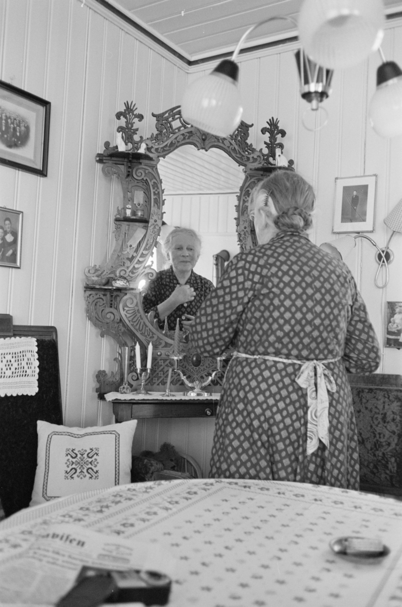 En kvinne ser seg i speilet i en stue på Røros.