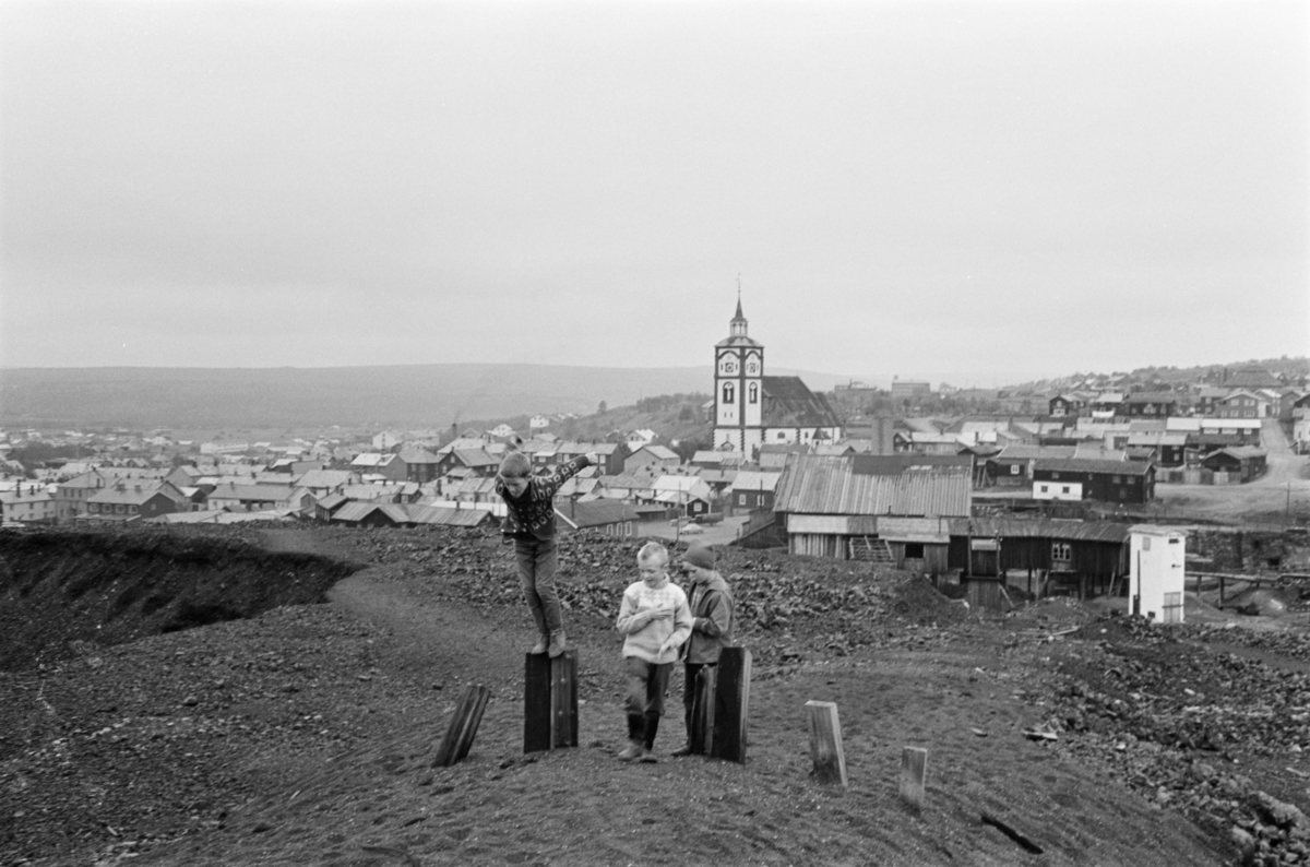 Barn leker i slagghaugene ved Røros. Kirken sees i bakgrunnen.