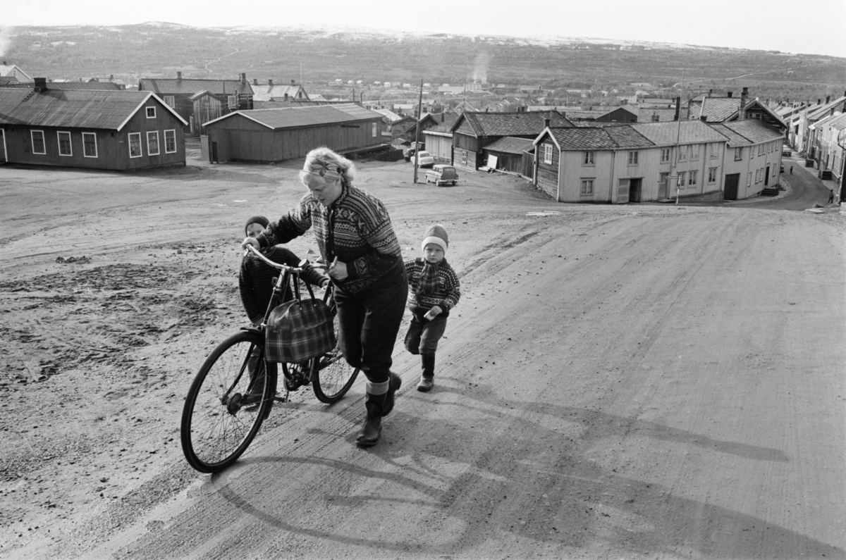 En kvinne og et barn med sykkel går i en gate på Røros.