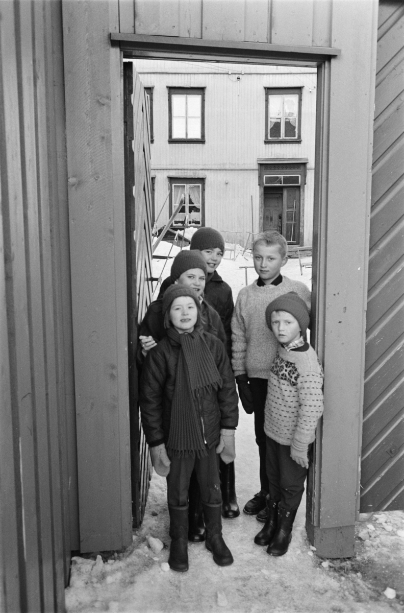 Fem barn står i en portåpning på Røros.