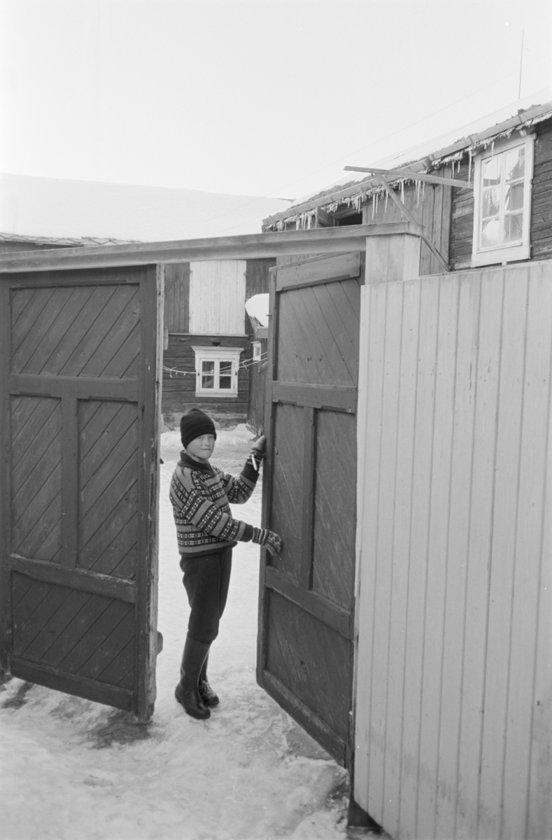 Et barn står i en port på Røros.